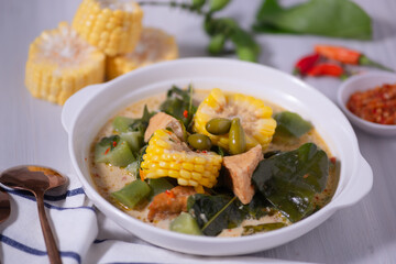 Sayur Lodeh is a vegetable dish made with coconut milk that is typical of Indonesia, especially in Central Java and DI Yogyakarta. Served in a bowl on a white table. Selective focus.