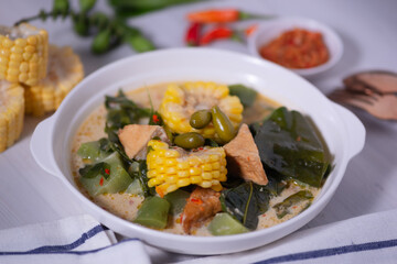 Sayur Lodeh is a vegetable dish made with coconut milk that is typical of Indonesia, especially in Central Java and DI Yogyakarta. Served in a bowl on a white table. Selective focus.