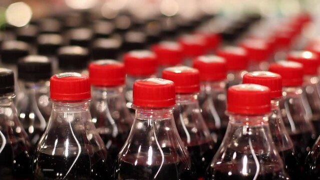 Rows of Plastic Bottles with Drinks at Supermarket Shelf. Many packages with cola in Warehouse. Close-up