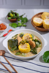 Sayur Lodeh is a vegetable dish made with coconut milk that is typical of Indonesia, especially in Central Java and DI Yogyakarta. Served in a bowl on a white table. Selective focus.