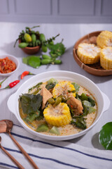 Sayur Lodeh is a vegetable dish made with coconut milk that is typical of Indonesia, especially in Central Java and DI Yogyakarta. Served in a bowl on a white table. Selective focus.
