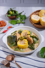 Sayur Lodeh is a vegetable dish made with coconut milk that is typical of Indonesia, especially in Central Java and DI Yogyakarta. Served in a bowl on a white table. Selective focus.