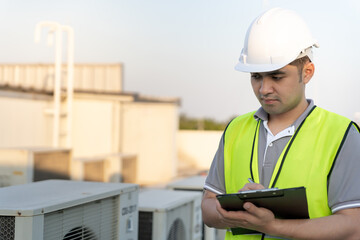 Asian maintenance engineer works on the roof of factory. contractor inspect compressor system and...