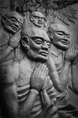 A group of Buddhist monks praying statues in front of a reclining Buddha.