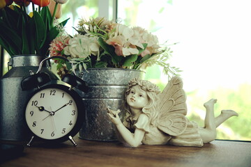 Angel statues home decoration with alarm clock and flowers in metal vase