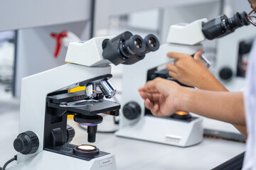 A person is using a microscope with a red and white background