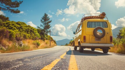 Vintage yellow van traveling on mountain road under clear blue sky