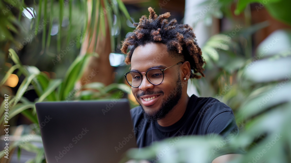 Poster young man using laptop and smiling at home. man sitting by table working on laptop computer.