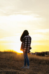 Young woman dressed in vintage clothing watching the sunset in the field