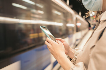 Young woman watching mobile waiting the metro. close-up. Metro arriving