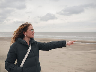 Woman Pointing Towards the Sea on a Cloudy Beach