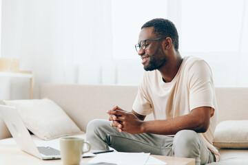 Smiling African American Freelancer Working on Laptop in Modern Home Office A young African...