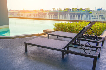 Scene of modern rest area pool chaise lounge buildings and condominium in city downtown day