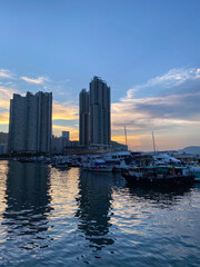 Naklejka premium Sunset Silhouettes Over Serene Harbor Cityscape