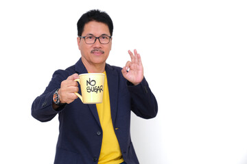 A man wearing a dark blazer over a yellow t-shirt is holding a cup with the words 'no sugar'