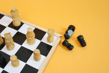Chess Pieces on Chess Board Isolated on Yellow Background