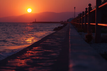 Obraz premium landscape of mediterrean sea coast at sunset, red sky, mountains in background, photorealistic // ai-generated 