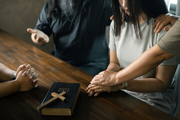 Woman gathered with her Christian friends in church, Bible close as they joined in prayer, feeling...