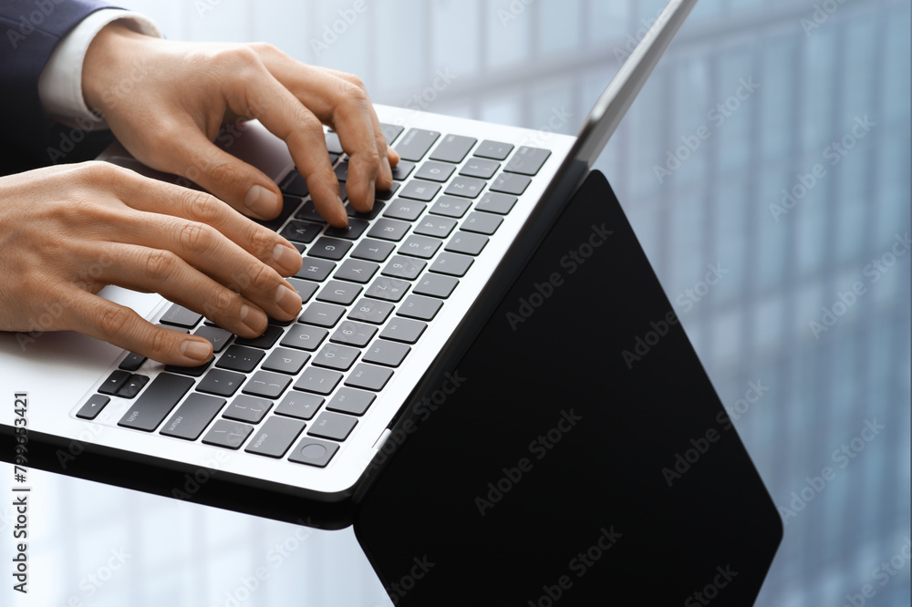 Poster businessman using laptop at office. closeup of hands typing . windows of building reflected on desk.