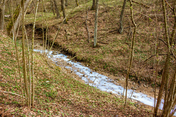 A ravine in which a blue stream flows after the illegal dumping of pollutants