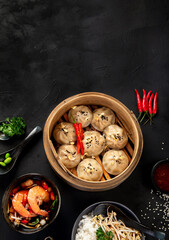 Chinese hot food. Dumplings, soy sauce, shrimp on black background. Traditional asian lunch