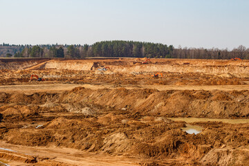 View of an active sand quarry with machinery working in the distance