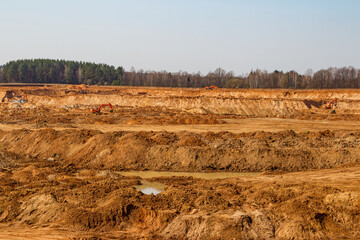 View of an active sand quarry with machinery working in the distance