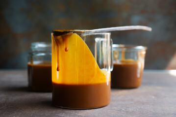 Freshly made homemade caramel sauce in a pitcher on rustic table