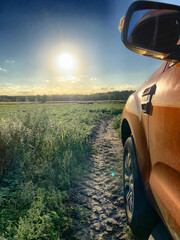 The image captures a picturesque rural scene at sunset with a strong sunlight flare. The right side...
