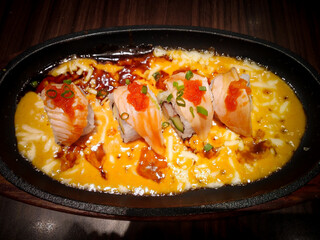 Close-up shot of Japanese rolls sizzling on a hot iron plate at a Japanese restaurant, with a blurred background