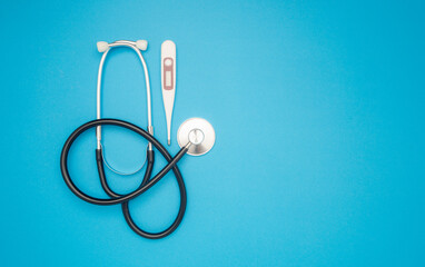 Stethoscope and a medical thermometer on a blue background.