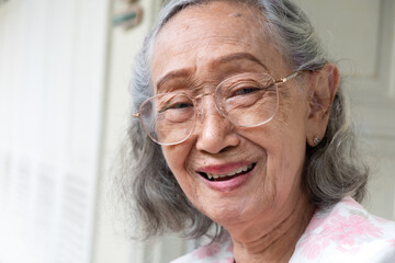 Healthy Southeast Asian elderly woman in glasses smiling and looking at camera