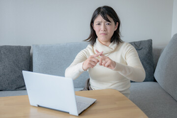 パソコン前でバツを出す若い女性