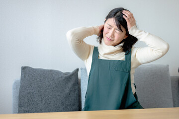 頭を抱える若いエプロン女性 © YUTO PHOTOGRAPHER