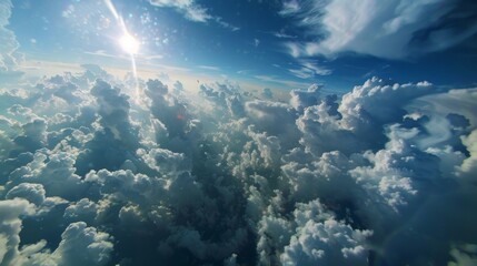 The sun can be seen shining brightly above a layer of fluffy clouds in the sky. The rays of sunlight are casting a warm glow on the cloud tops.