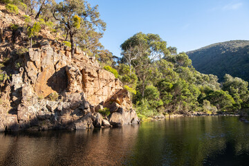Natural swimming hole against steep and rocky cliffs at Grahams Dam surrounded by Australian native...
