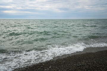 An incoming wave on the Black Sea and a pebble beach on the Sochi coast on a summer day with...