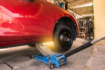 Red Car waiting for tire change, vehicle inspection In car service center garage car has spare wheel for repairs and set the distance on car lift to auto automotive service automobile factory