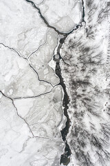 Aerial view of a frozen surface of a river, with its intricate network of cracks and ice formations creating a mesmerizing minimalist pattern.