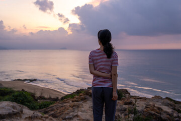 A woman standing at beach and looking to sunrise.