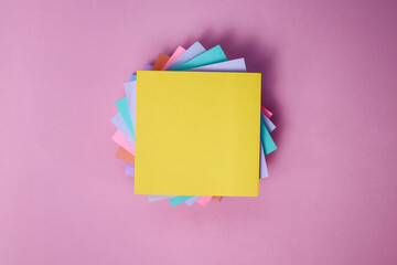 Top View of Stacks of Colorful Sticky Notes with Yellow Color Notes in Front Isolated on Pink...