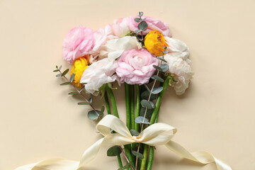 Beautiful bouquet of ranunculus flowers with eucalyptus and bow on beige background