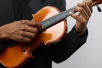 Close up of a elegant man in formal attire playing violin on white background in studio setting