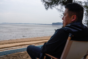 A person sitting leisurely on a beach chair by the sea