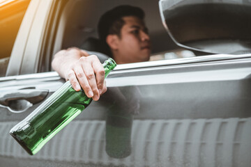 Drunk man driving a car on the road holding bottle beer Dangerous drunk driving concept