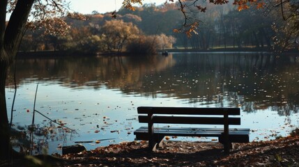 A wooden bench is placed on the sandy shore of a calm lake. The bench overlooks the water, providing a resting spot for visitors to enjoy the view and peaceful surroundings.