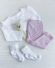 Obraz na płótnie Canvas Set of baby bodysuits, pants, socks and knitted toy