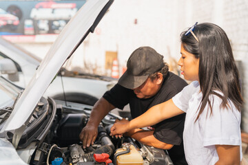 Woman helping a mechanic to repair a car