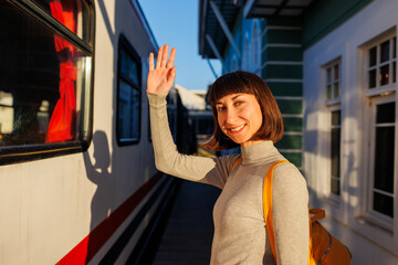young traveler with a backpack stands on the platform and says goodbye, saying goodbye before leaving.