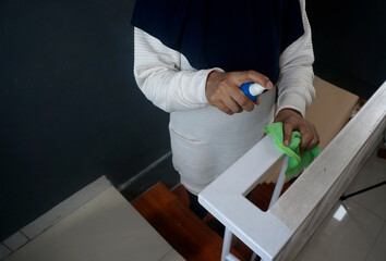 Close-up of a woman cleaning the stair railing with micro fiber cloth and detergent spray
